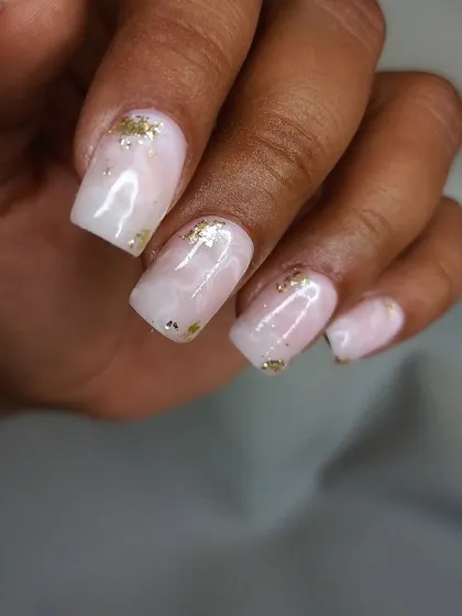A close-up of the pink quartz and gold foil nails, showing the soft, blended colors and a glossy finish.