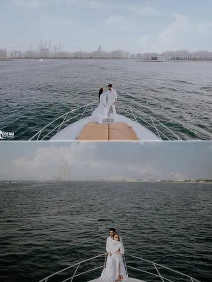 A wide-angle shot capturing the couple on a yacht, showcasing the vastness of the sea and the distant, iconic silhouette of the Burj Al Arab.