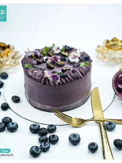 Another angle of the fresh Blueberry cake, set for a celebration with golden cutlery. The fresh berries and flowers make it a perfect summer treat.