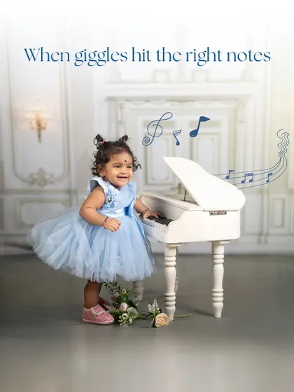 When giggles hit the right notes. This shot captures a moment of pure happiness as a little girl in a blue dress plays at the piano, her joy lighting up the elegant room.