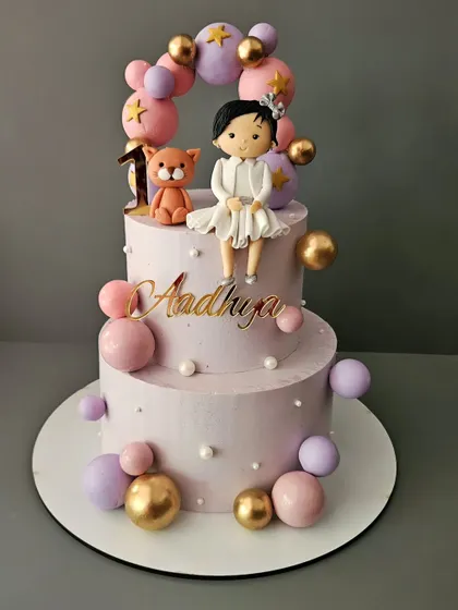 A beautiful two-tier cake for Aadhya's first birthday. This vanilla strawberry cake is decorated with a balloon arch and a cute figurine.