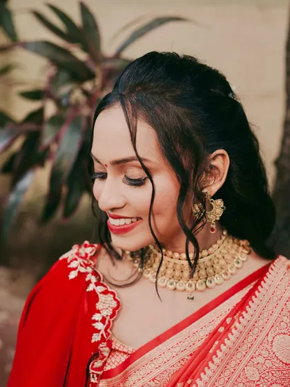 A close-up of her makeup and hair. The soft red lip, subtle eye makeup, and romantic tendrils framing her face create a look that is both traditional and modern.