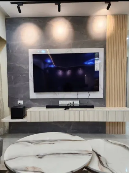 A close-up of the TV unit, showing the combination of a grey marble-finish back panel, light wood fluting, and a floating console.