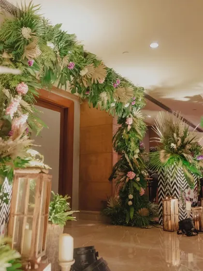 A grand entrance for a jungle-themed cocktail party, featuring a lush arch of tropical leaves and flowers.