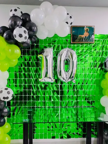 A football-themed party with a green shimmer backdrop to look like grass, with silver foil numbers for a 10th birthday.