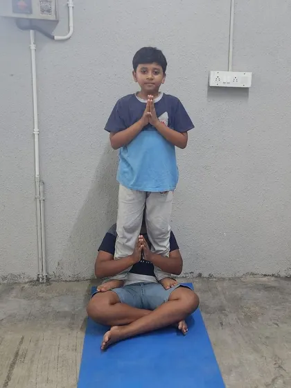 A coach provides a stable base for a young camper, ensuring a safe and positive first experience with acro-yoga.