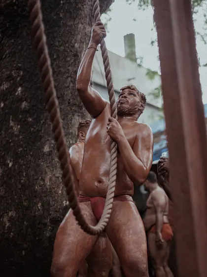 Wrestlers are seen using thick ropes for strength training, their muscles straining with the effort. These images highlight the rigorous physical conditioning that is part of the daily routine.
