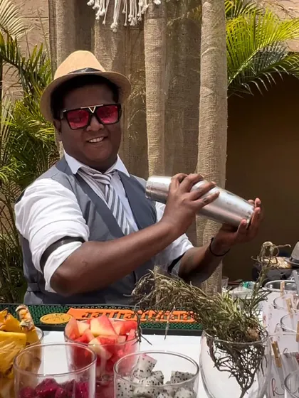 A bartender shakes up a tropical cocktail at a Bohemian-themed event. We use fresh fruits and high-quality ingredients to craft delicious drinks that complement the theme.