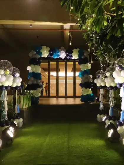 The beautifully lit entrance pathway for the starry night party. The path is lined with balloon bouquets topped with confetti and disco ball balloons, illuminated by spotlights.