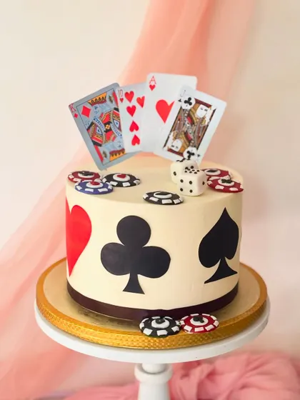 A casino-themed cake perfect for a poker night or milestone birthday. The design includes fondant playing cards, dice, and poker chips on a buttercream cake decorated with card suits.