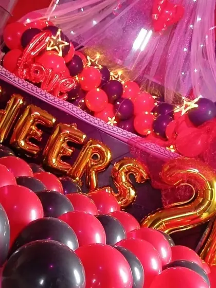 A close-up of the 'Cheers' foil balloons and the dense arrangement of red and black balloons on the floor, showing the detail that goes into filling the space.
