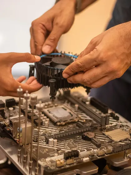 With my guidance, a student installs the CPU cooling fan onto the motherboard. This is a critical step that teaches them about heat management in electronics.