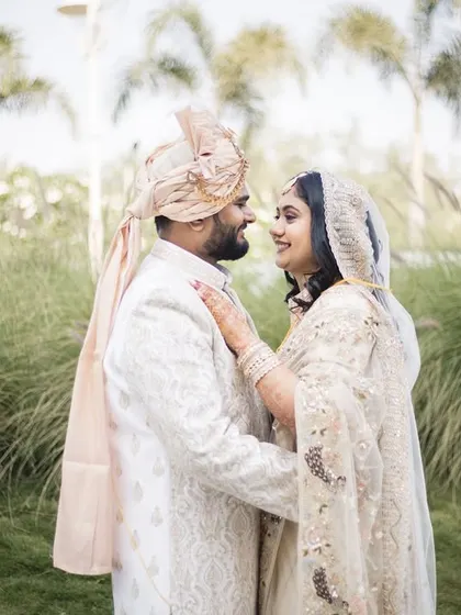 A quiet look shared between Ayushi and Abhiram, dressed in elegant white for their wedding day.