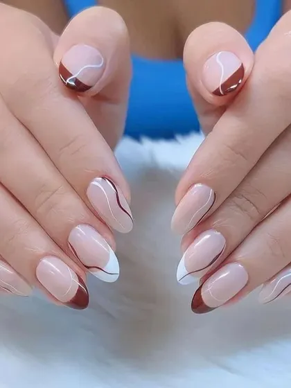 A sophisticated design with a mix of brown and white French tips, accented with delicate, abstract swirls.