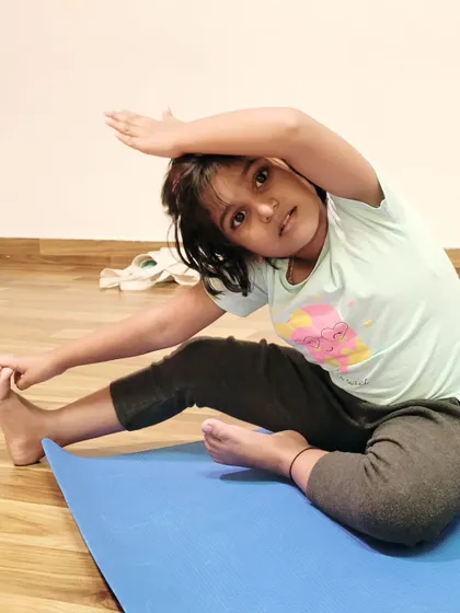 A young girl demonstrates a beautiful side stretch, showing great flexibility and body awareness.