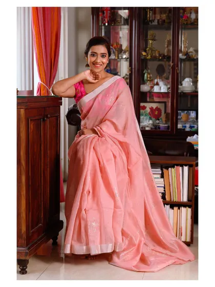 A warm and friendly portrait of a model in a pink saree. The smile and comfortable pose make the image feel inviting and genuine.