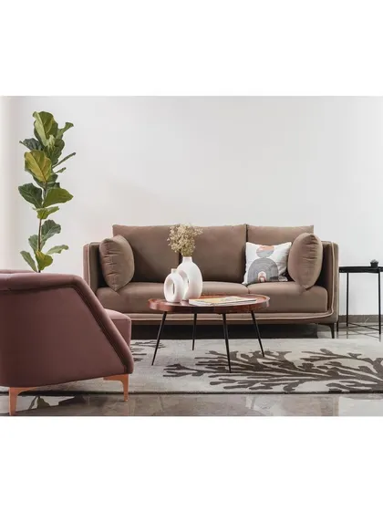 A wider view of the minimalist living area in the 'House Under Tabebuia Trees', where a simple sofa and armchair are arranged to create an open, uncluttered feel.