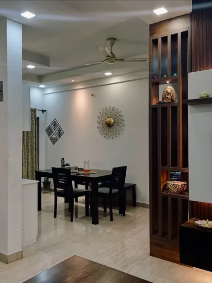A view from the living room into the dining area, showcasing the wooden partition that provides visual separation while allowing light to flow through.