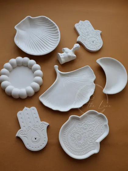 A collection of my eco-resin sculptures and trinket trays, including Hamsa hands, a Ginkgo leaf, and a female bust.