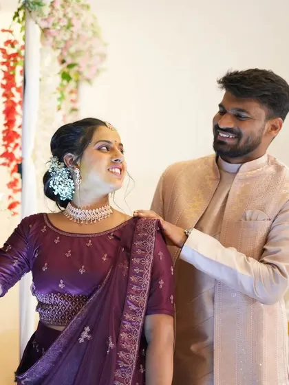A sweet moment between a couple, captured in front of the stage decor. The hanging red and white flowers add a touch of romance to the background.