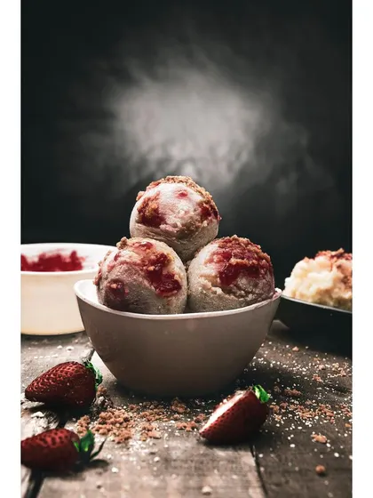 Scoops of strawberry ice cream in a bowl, captured with dramatic backlighting to highlight the texture and smoke effect. This kind of creative food photography is effective for dessert brands and promotional content.