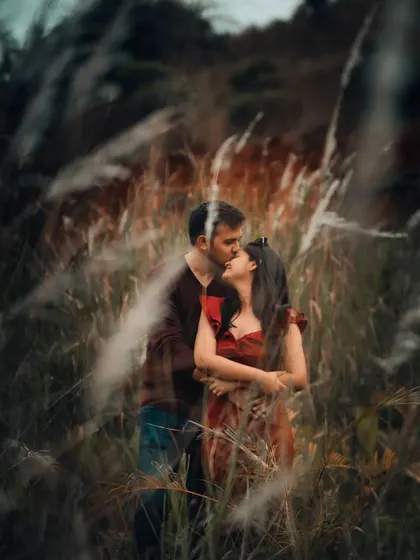 A dreamy, intimate pre-wedding photo of a couple in a field of tall grass, creating a sense of being lost in their own world.