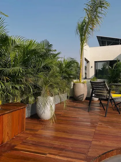 The rich tones of the wooden deck in this Faridabad project are complemented by the lush greenery and modern outdoor furniture, creating a warm and inviting space.