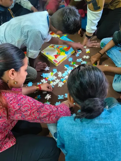 Teamwork makes the dream work. Children and volunteers work together to solve a puzzle, an activity that teaches collaboration, problem-solving, and patience.