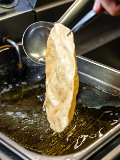 A crispy Kerala papad being lifted from the hot oil at Kari Apla. This shot captures a specific cultural dish in a dynamic way.
