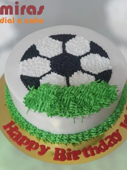 A simple yet classic football cake. The design features a soccer ball on a field of green grass frosting, making it a perfect and delicious treat for any football fan's birthday.