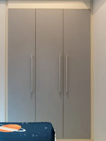 A shot of the minimalist three-door wardrobe in a neutral gray, designed to be timeless and adapt to changing decor themes.