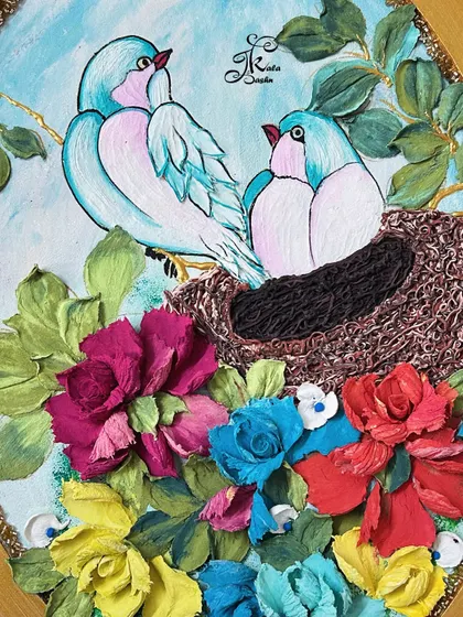 A close-up of another bird-themed piece, this time with two cute blue birds in their nest. The nest itself is sculpted with textured plaster to look like woven twigs, surrounded by a vibrant floral base.