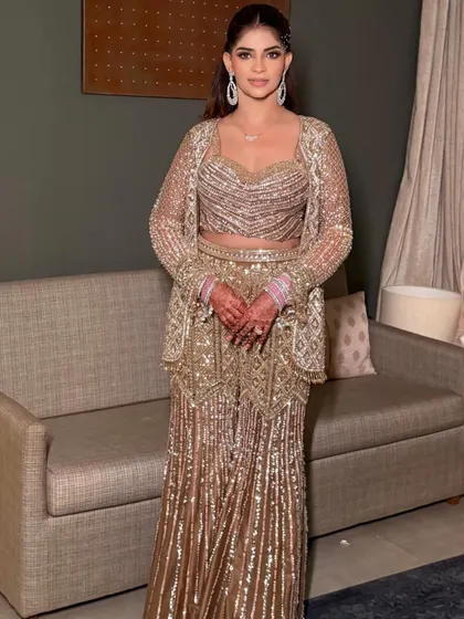 The full-length view shows how the dramatic high ponytail complements the shimmering, modern ethnic outfit perfectly.