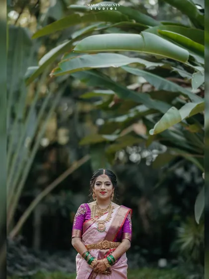 A stunning full-length portrait of the bride, Namratha, in her beautiful pink and purple saree, set against a backdrop of tropical plants.