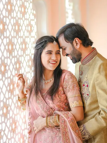 A bright and happy portrait of a couple sharing a candid moment. The genuine smiles and natural light through the intricate window create a warm and joyful photograph.