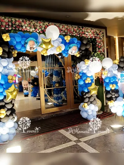 An impressive double balloon arch entrance for a "Boss Baby" party, using a classic blue, black, and white color scheme with character accents.