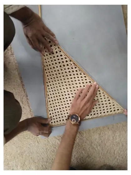The process of creating custom furniture involves many hands. Here, an artisan and I work together to perfectly fit a handwoven cane section into its frame, ensuring every detail is precise. This is a look into my collaborative design process.