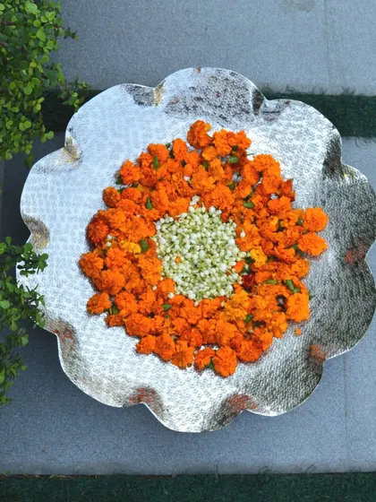 Our nickel-plated thal is perfect for festive decor. Here it is decorated with marigold and jasmine, creating a traditional and fragrant centerpiece.