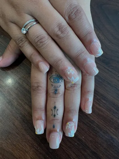 Sometimes, beauty lies in the details. This design showcases a subtle and natural look with delicate, hand-painted white floral art on a clean, translucent base. It's the perfect choice for an elegant, everyday manicure that feels personal and refined.