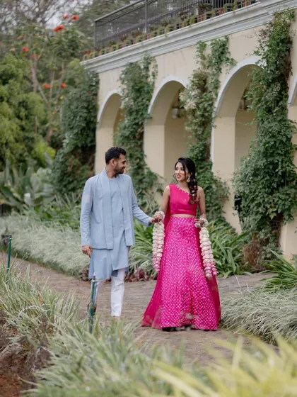A couple walking hand-in-hand through the beautiful gardens of Sula Vineyards. This shot captures a relaxed moment against a lush, scenic backdrop.