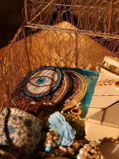 A detail shot showing the embroidered evil-eye coasters inside the golden wire box.