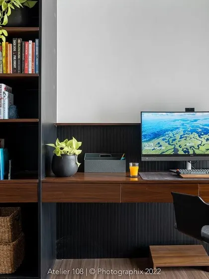 Home offices are trendier than ever. This sleek workspace features a dark wood desk with integrated shelving, providing ample storage and a sophisticated environment for productivity. The greenery adds a touch of life.