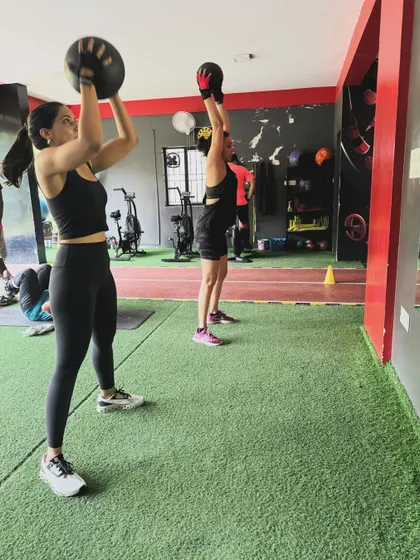Two clients perform overhead medicine ball throws in sync, adding a fun, coordinated element to their workout.