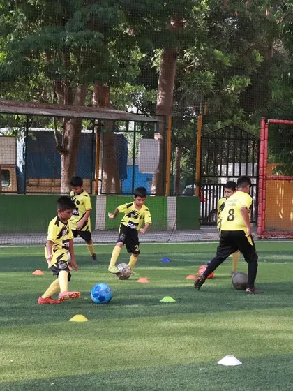 A wide shot of a drill in progress, with players practicing their dribbling and movement across the pitch.
