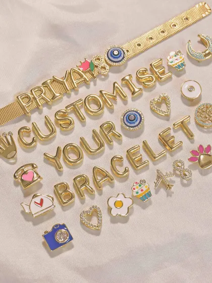 This is how it works. Lay out your letters and charms to create your perfect piece, like this 'PRIYA' bracelet with a teapot and evil eye charm.