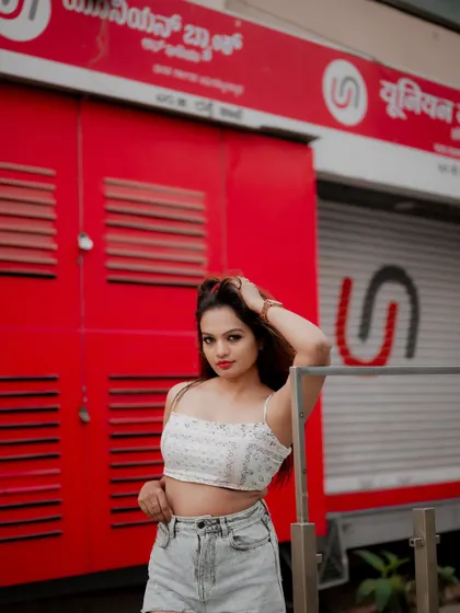 A full-length portrait of a model against a vibrant red wall. The composition is bold and perfect for making a fashion statement.