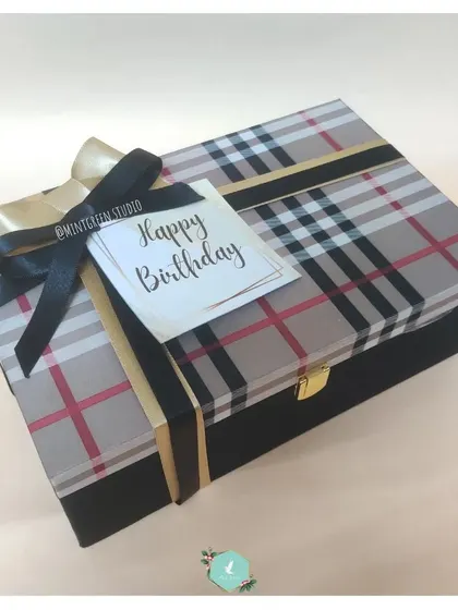A chic birthday gift box with a classic plaid pattern and a black ribbon. This stylish and reusable box is perfect for creating a memorable birthday surprise for anyone.