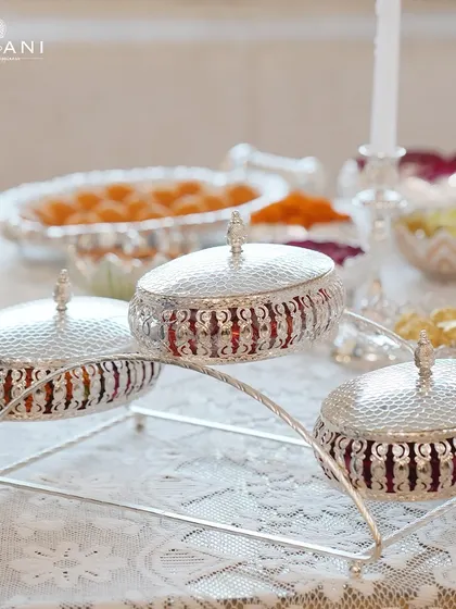 A three-tiered silver serving stand, perfect for displaying a variety of nuts and sweets during Diwali. This piece is both a practical and opulent addition to any festive table, showcasing abundance in style.