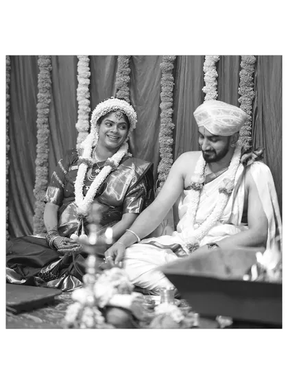 A black and white photograph capturing a quiet moment during a Seemantha ceremony. The couple sits together, participating in the rituals, with a look of serene happiness.