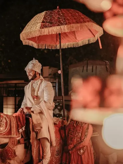 A royal groom's entrance on a decorated horse at night, a grand start to the wedding festivities.